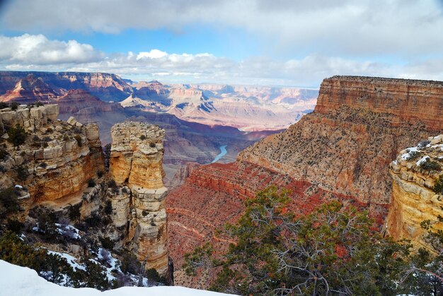 Vista panorámica del Gran Cañón en invierno con nieve y cielo azul claro.