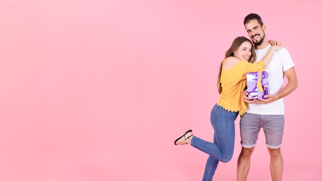 Vista panorámica de la mujer abrazando a su novio con caja de regalo