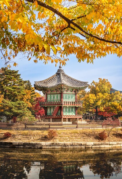 Vista panorámica del templo Gyeongbokgung en Corea con hojas otoñales en primer plano de ramas de árboles