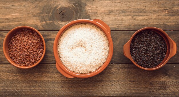 Vista panorámica de tres diferentes cuencos de arroz orgánicos en la mesa de madera