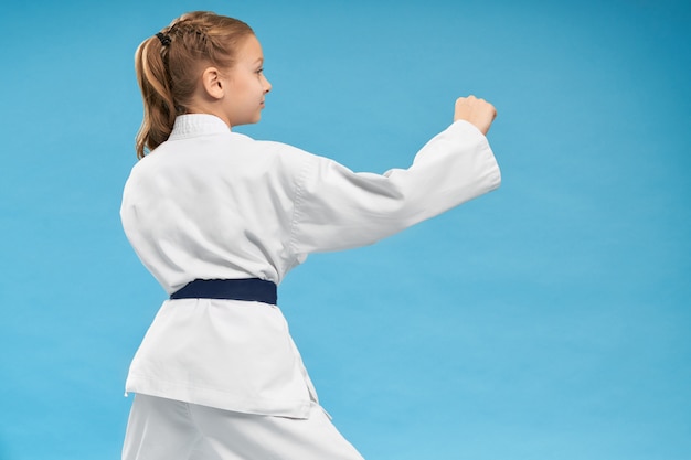 Vista desde la parte posterior de la niña haciendo karate sobre fondo aislado