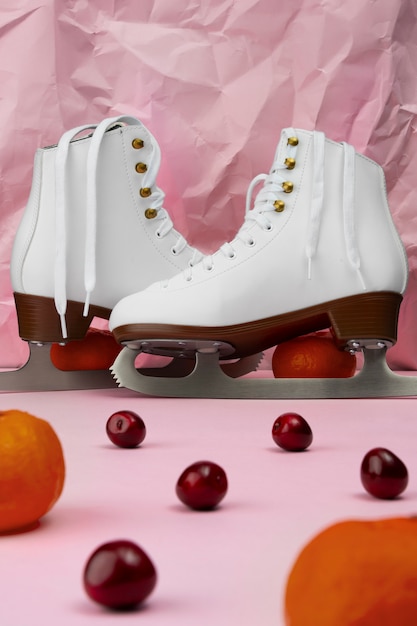 Vista de patines de hielo blancos con cerezas y mandarinas.
