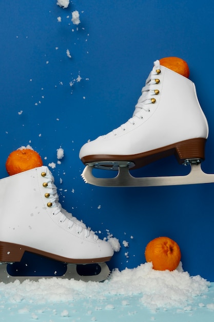 Foto gratuita vista de patines de hielo blancos con mandarinas y nieve.