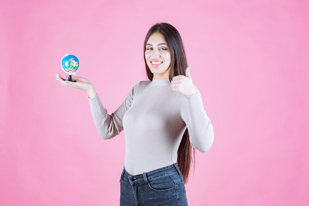 Vista de perfil de una niña sosteniendo un mini globo con confianza