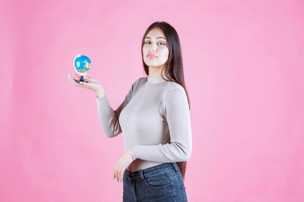 Vista de perfil de una niña sosteniendo un mini globo con confianza