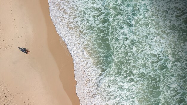 Vista de personas en la costa y olas de espuma.