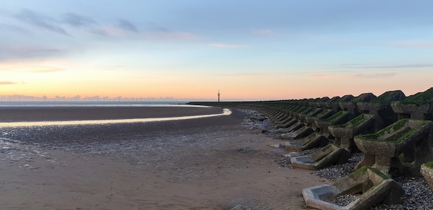 Vista de la playa en Liverpool al atardecer, filas de rompeolas, Reino Unido