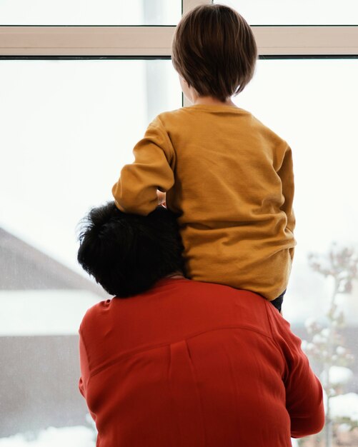 Vista posterior de la abuela y el nieto mirando por la ventana