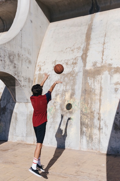 Foto gratuita vista posterior de un adolescente practicando baloncesto