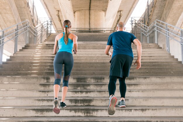 Vista posterior del atleta masculino y femenino para correr en la escalera