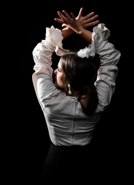 Vista posterior bailarina de flamenco levantando las manos