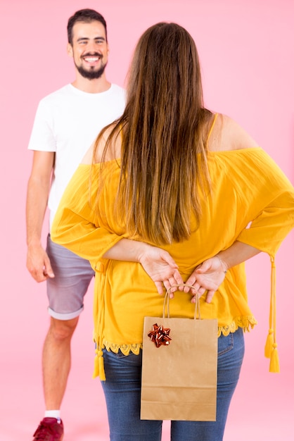 Vista posterior de la bolsa de papel de compras de mujer escondida con lazo rojo de su novio