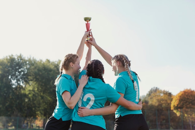 Vista posterior chicas levantando un trofeo