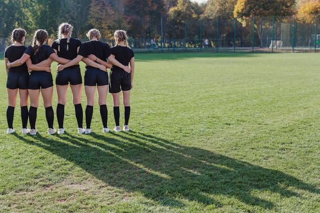 Vista posterior chicas de pie en un campo de fútbol