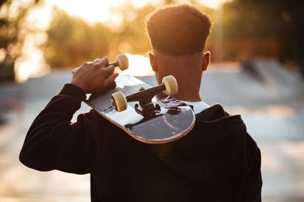Vista posterior de un chico adolescente masculino con patineta