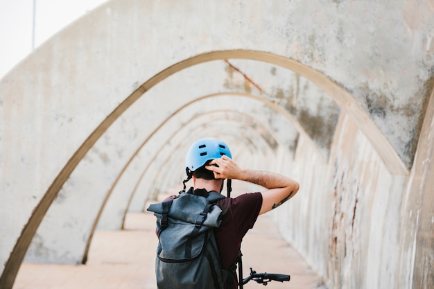 Foto gratuita vista posterior de un ciclista poniéndose el casco.