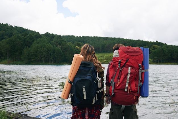 Vista posterior de dos excursionistas con mochilas frente al agua