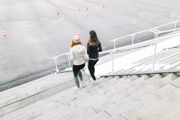 Vista posterior de dos mujeres corriendo en la escalera en el invierno