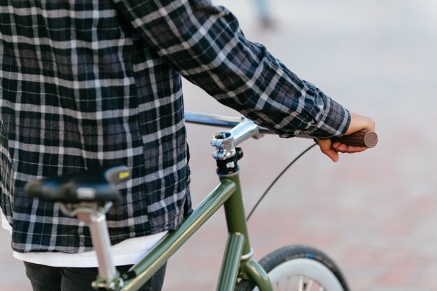 Vista posterior en elegante hombre de pie con bicicleta al aire libre.