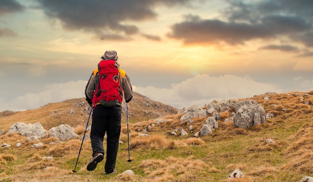 Vista posterior de un excursionista mirando la puesta de sol desde una montaña