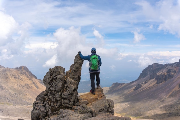 Vista posterior de un excursionista con una mochila verde en la cima del volcán Iztaccíhuatl