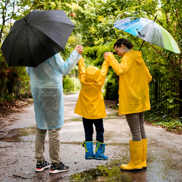 Foto gratuita vista posterior familia divirtiéndose mientras llueve