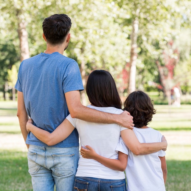 Vista posterior de la familia con los padres y el niño abrazados