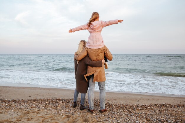 Vista posterior de una familia sonriente con una pequeña hija