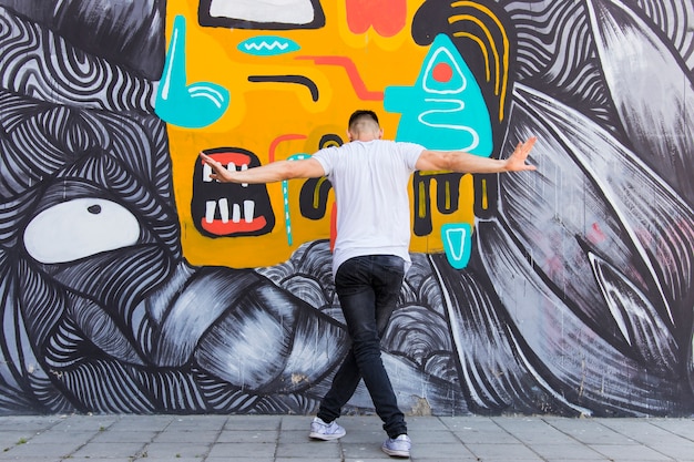 Vista posterior de un hombre bailando en el contexto creativo de la pared
