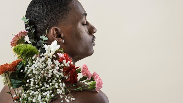 Foto gratuita vista posterior del hombre sin camisa posando con ramo de flores y espacio de copia