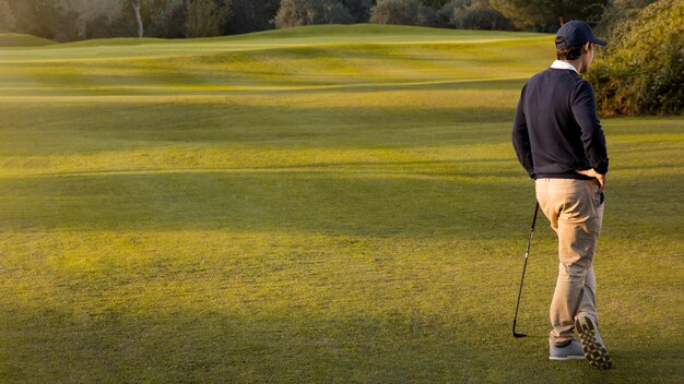 Vista posterior del hombre en el campo de golf cubierto de hierba con espacio de copia