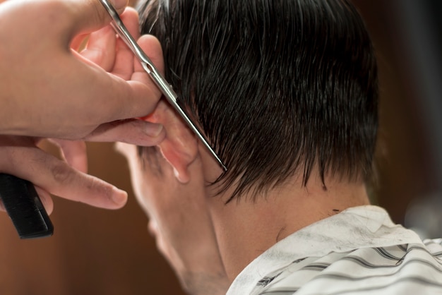 Vista posterior de un hombre cortándose el pelo