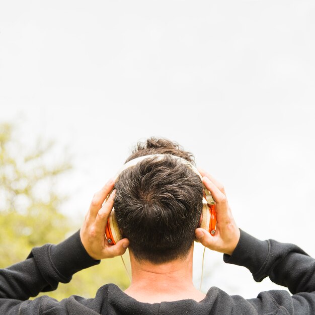 Vista posterior de un hombre escuchando música en auriculares al aire libre