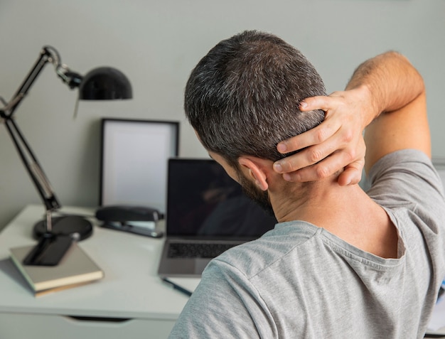 Foto gratuita vista posterior del hombre estirando mientras trabaja desde casa