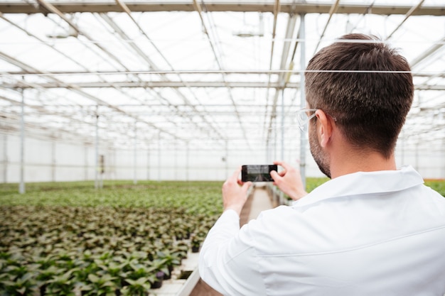 Foto gratuita vista posterior del hombre haciendo fotos de vegetación