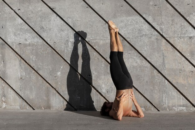 Vista posterior del hombre haciendo yoga al aire libre