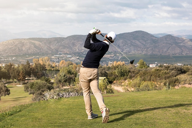 Vista posterior del hombre jugando al golf en el campo