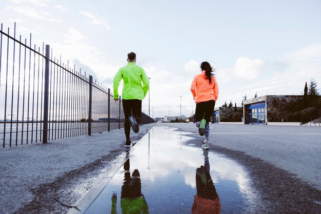 Vista posterior de un hombre y una mujer corriendo en la calle