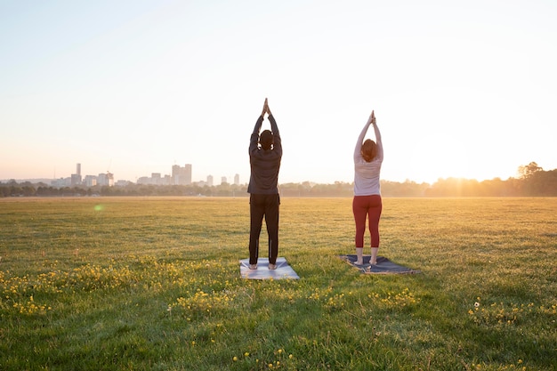 Vista posterior del hombre y la mujer haciendo yoga juntos al aire libre