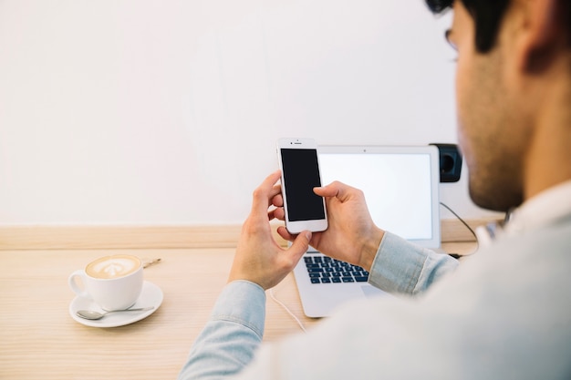 Vista posterior del hombre que trabaja con teléfono inteligente