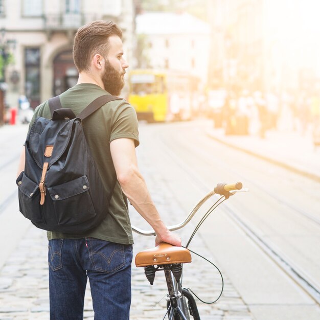 Vista posterior de un hombre con su bicicleta en la ciudad