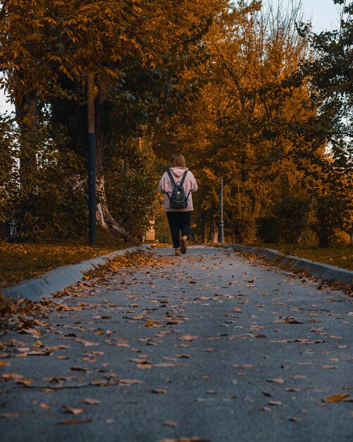 Vista posterior de una joven adolescente caminando en un parque en un día de otoño