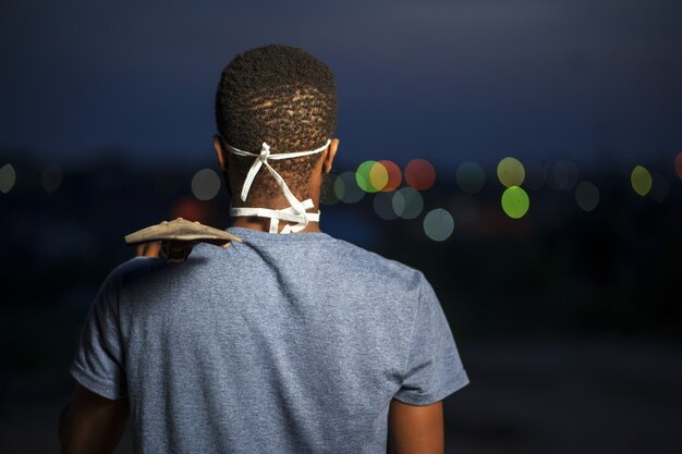 Vista posterior de un joven afroamericano en una mascarilla protectora sosteniendo una pala