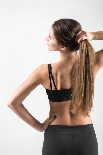 Vista posterior de la joven mujer sosteniendo su cabello en brazos