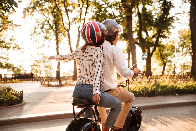 Vista posterior de la joven pareja africana monta en moto moderna en el parque