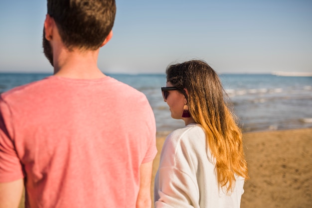 Vista posterior de una joven pareja caminando en la playa