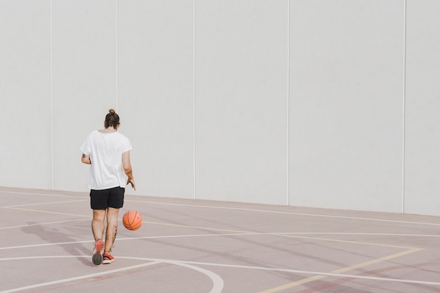 Vista posterior de un joven praticing baloncesto