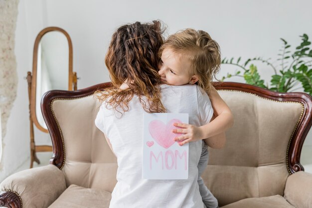 Vista posterior de la madre abrazando a su hija en el día de la madre.