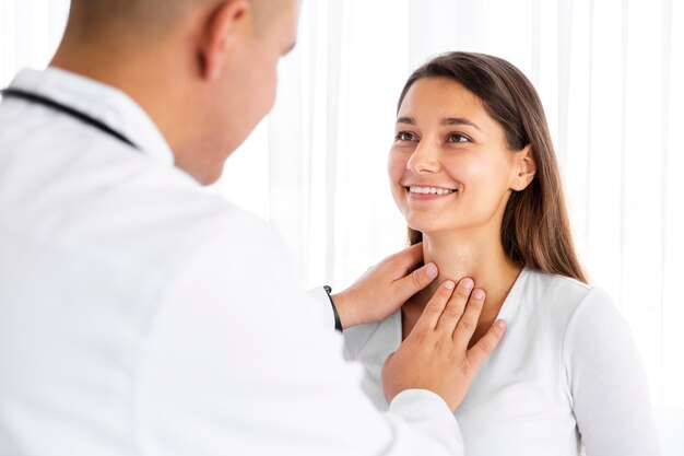 Vista posterior médico examinando el cuello de la mujer