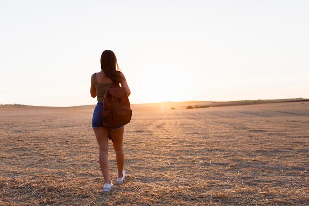 Vista posterior de la mujer al aire libre en la naturaleza hacia la puesta de sol